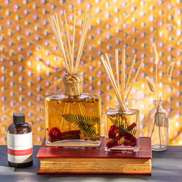 Large and Small Rosy Rings Spicy Apple Scented Reed Diffuser displayed next to Diffuser Refill Bottle